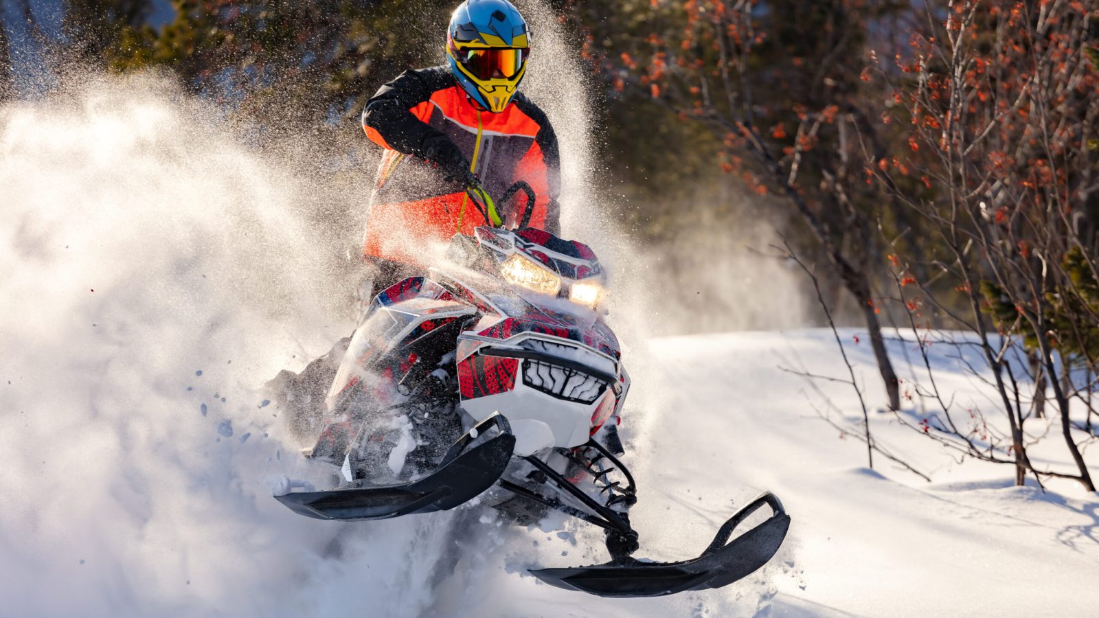 An exhilarating shot of a man enjoying the thrill of snowmobiling, dashing through the snowy landscape.